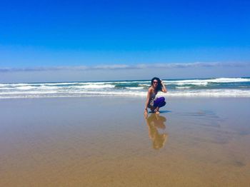 Young woman standing on beach against sky