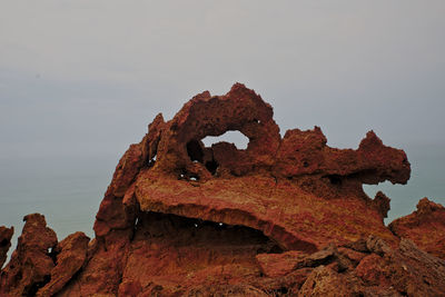 Close-up of rusty metal on rock against sky