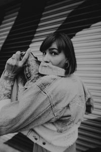 Portrait of young woman standing against the wall