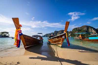 Boats moored on beach against sky