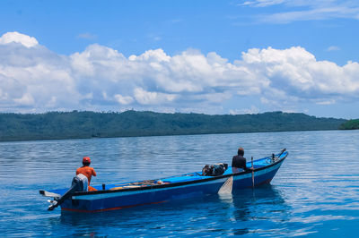 People on boat in sea against sky