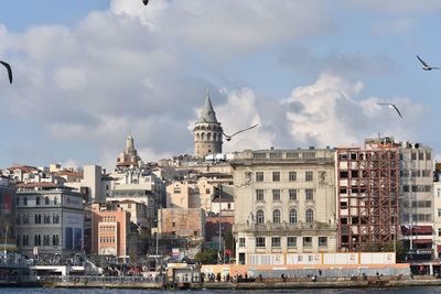 Buildings in city against cloudy sky