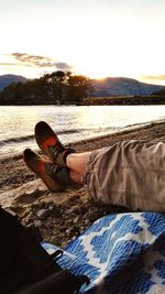 Portrait of man relaxing on sand at sunset