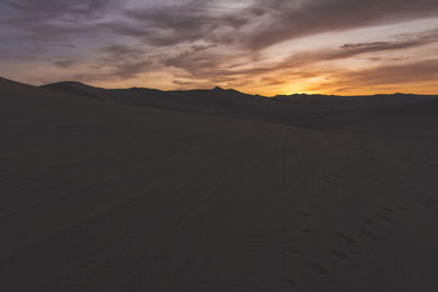 Foot prints with tire tracks on sand in desert