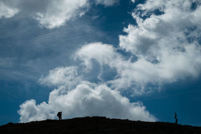 Low angle view of silhouette people standing against sky
