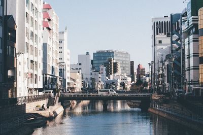 Bridge over river in city against sky