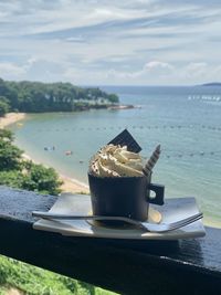 Close-up of dessert on table by sea against sky