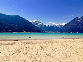 Scenic view of sea and mountains against clear blue sky