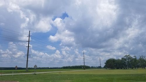 Panoramic view of electricity pylon on field against sky