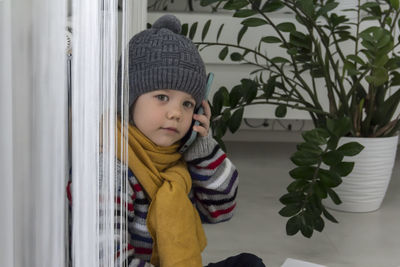 A small child with a yellow scarf near the radiator speaks on the phone.  energy crisis concept