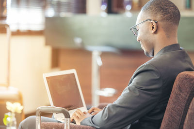 A black man works on a tablet computer in the hotel lobby.