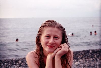 Portrait of smiling young woman against sea at beach