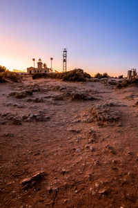 Factory on field against sky during sunset
