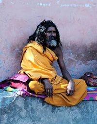 Full length of woman sitting against wall