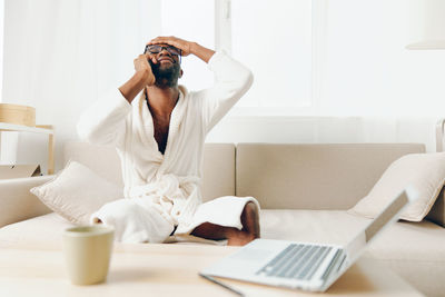 Young woman using mobile phone while sitting at home