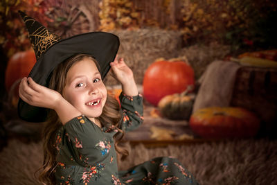 A beautiful 6-7-year-old girl tries on a witch hat. he laughs and shows a toothless smile 
