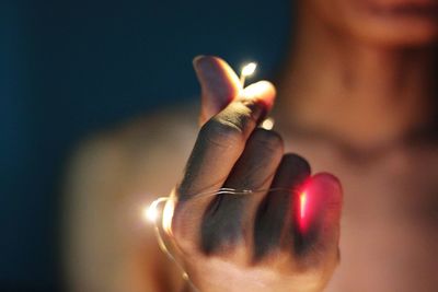 Close-up of hand holding illuminated candle