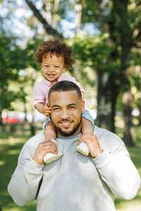 Portrait of man giving piggyback to baby boy at park