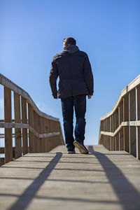 Rear view of man standing on footbridge