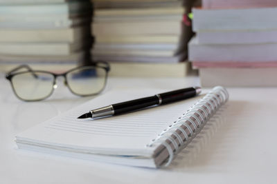 Close-up of pen on open blank book at table