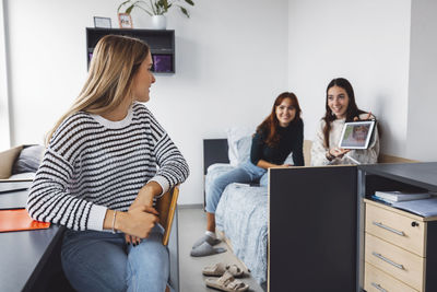 Smiling friends using laptop while sitting at office