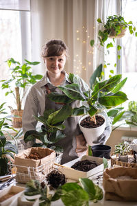 Portrait of smiling woman holding potted plant