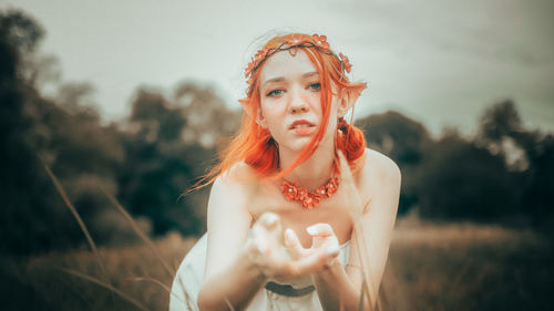 Portrait of young woman standing against sky