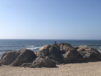 Rocks on beach against clear sky