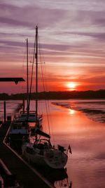 Boats moored at harbor during sunset