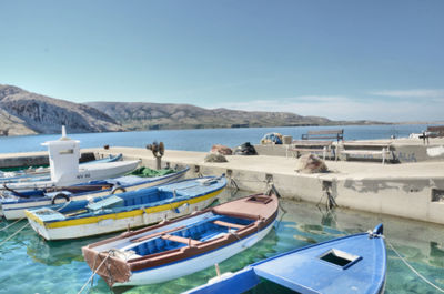 Boats moored on beach against blue sky