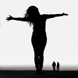 Rear view of silhouette women standing against sky