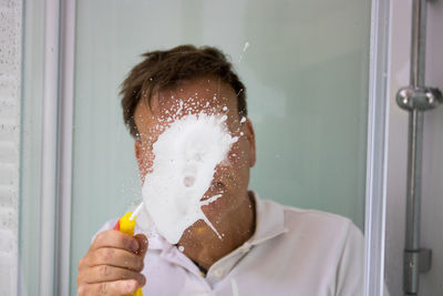 Mature man cleaning bathroom glass