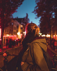 Rear view of woman walking on street at night