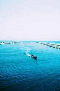 Boats sailing in calm sea against clear sky