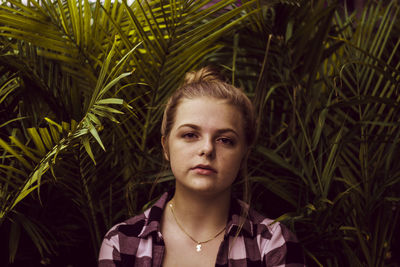 Close-up portrait of confident teenage girl against plants