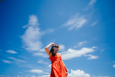 Low angle view of woman standing against blue sky