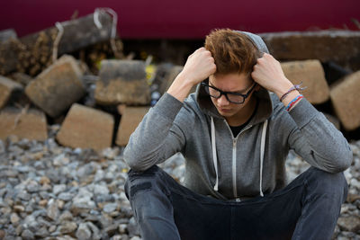 Full length of young man sitting on log