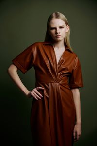 Portrait of young woman standing against wall