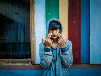 Portrait of young woman standing against blue wall