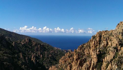 Scenic view of sea and mountains against clear blue sky