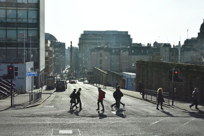 People walking on road against buildings in city