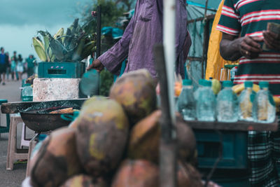 Market vendors standing at stall with coconuts in foreground