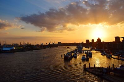 Boats moored on river against sky during sunset