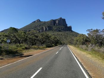 Road by trees against clear sky