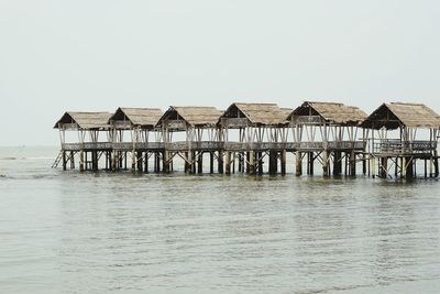 Stilt house in sea against clear sky