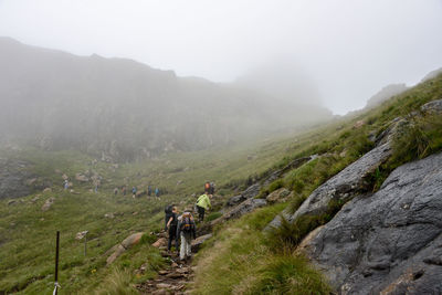 Hikers walking on mountain during foggy weather