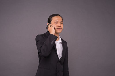 Smiling young woman standing against gray background