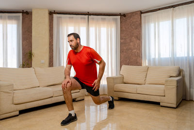 Full length of man sitting on sofa at home