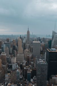 Aerial view of buildings in city against cloudy sky