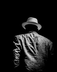 Rear view of man wearing hat against black background